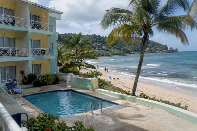 Pastel budget beachfront hotel with a small pool and palms