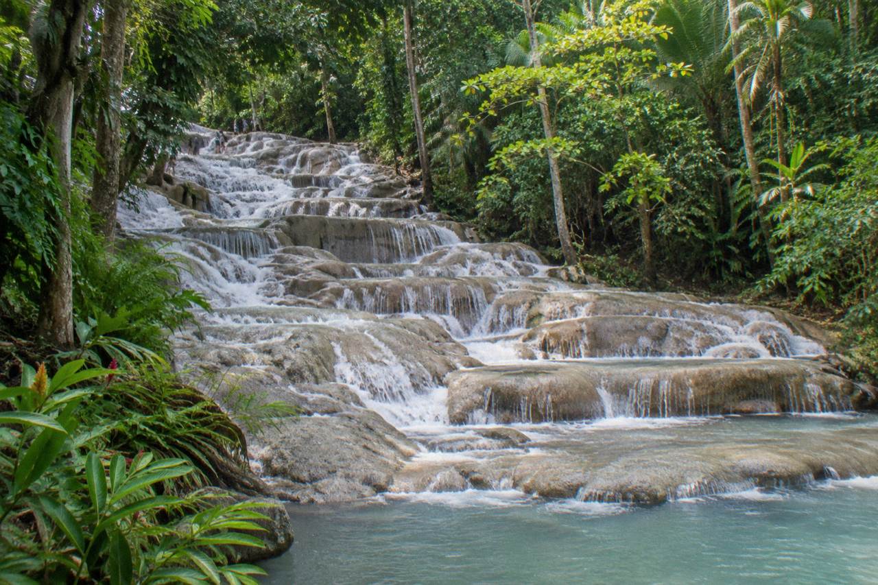 Terraced limestone waterfall cascading through tropical forest toward the Caribbean sea