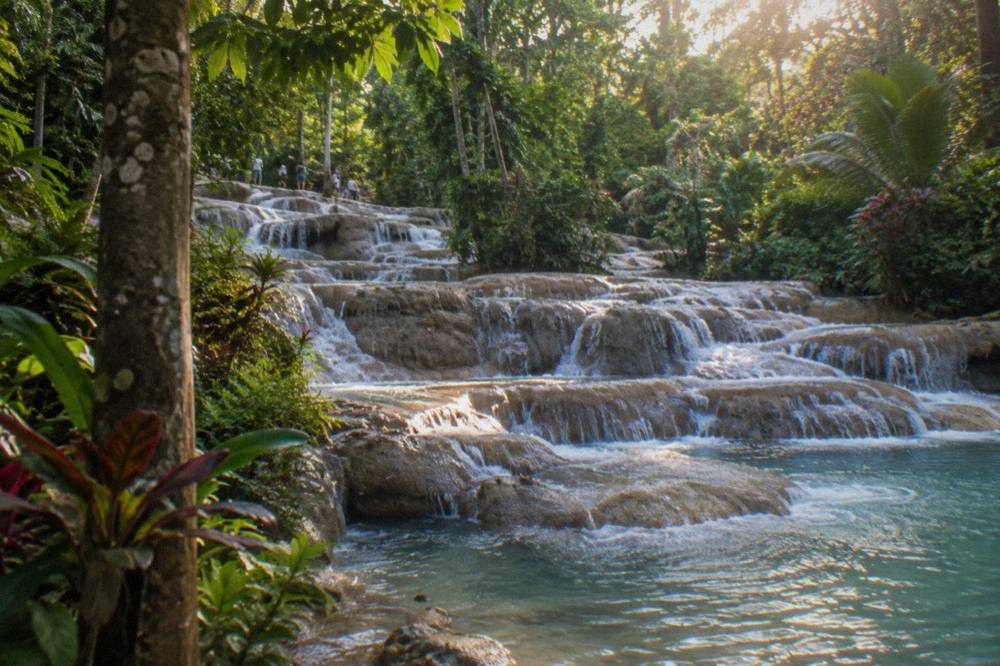 Swimsuits and quick-dry clothing drying on a railing beside a tropical waterfall