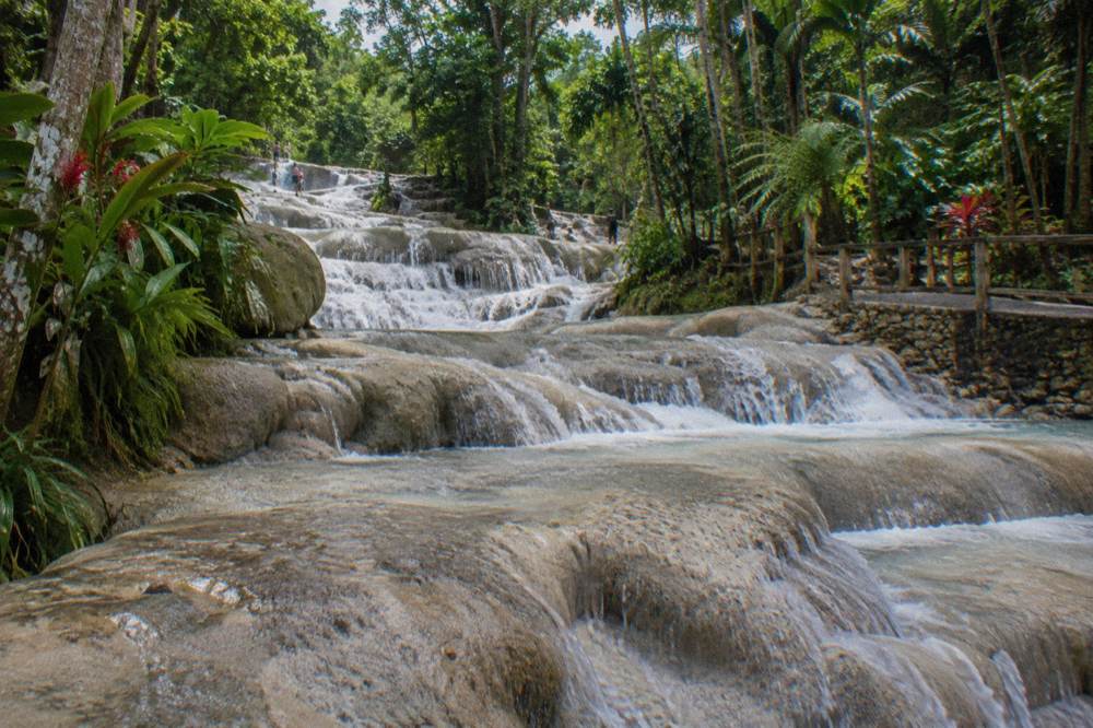 Closed-toe water shoes drying on rocks beside a natural waterfall pool