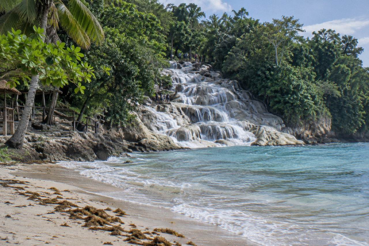 Waterfalls cascading in terraced steps toward a beach and the sea