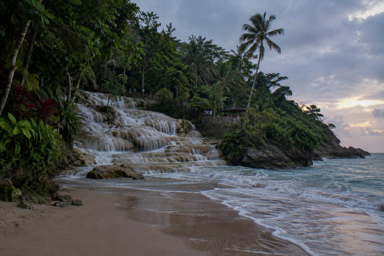Terraced waterfall cascading through a green tropical gorge toward the Caribbean sea