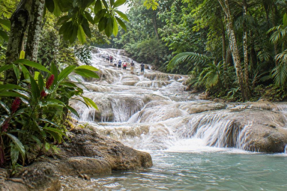 Row of visitors forming a chain in the water on the lower tiers of the falls