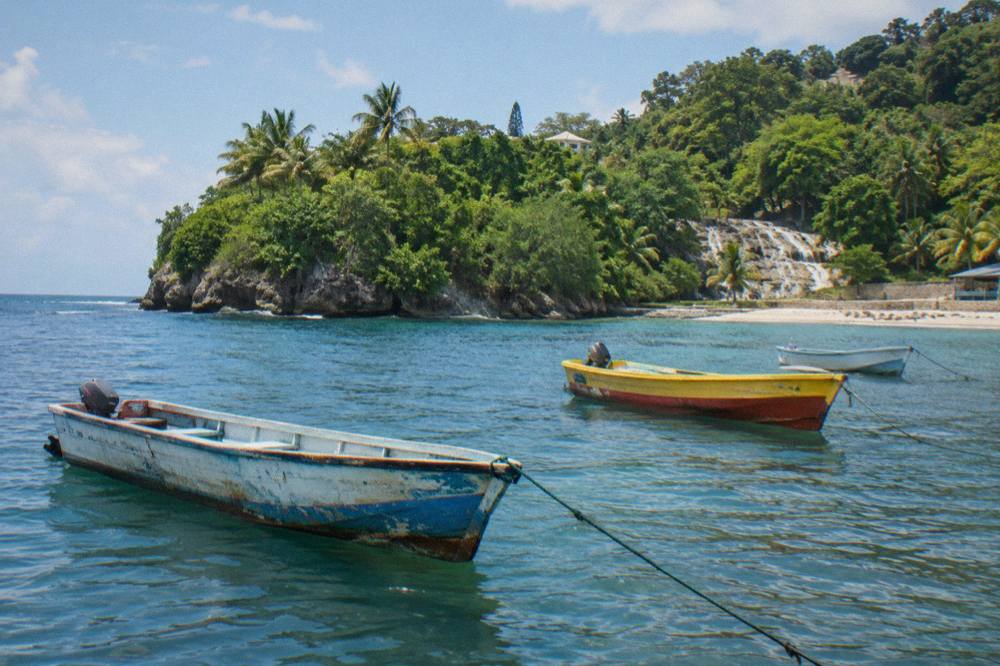 Calm Caribbean bay with fishing boats moored near a green headland at midday