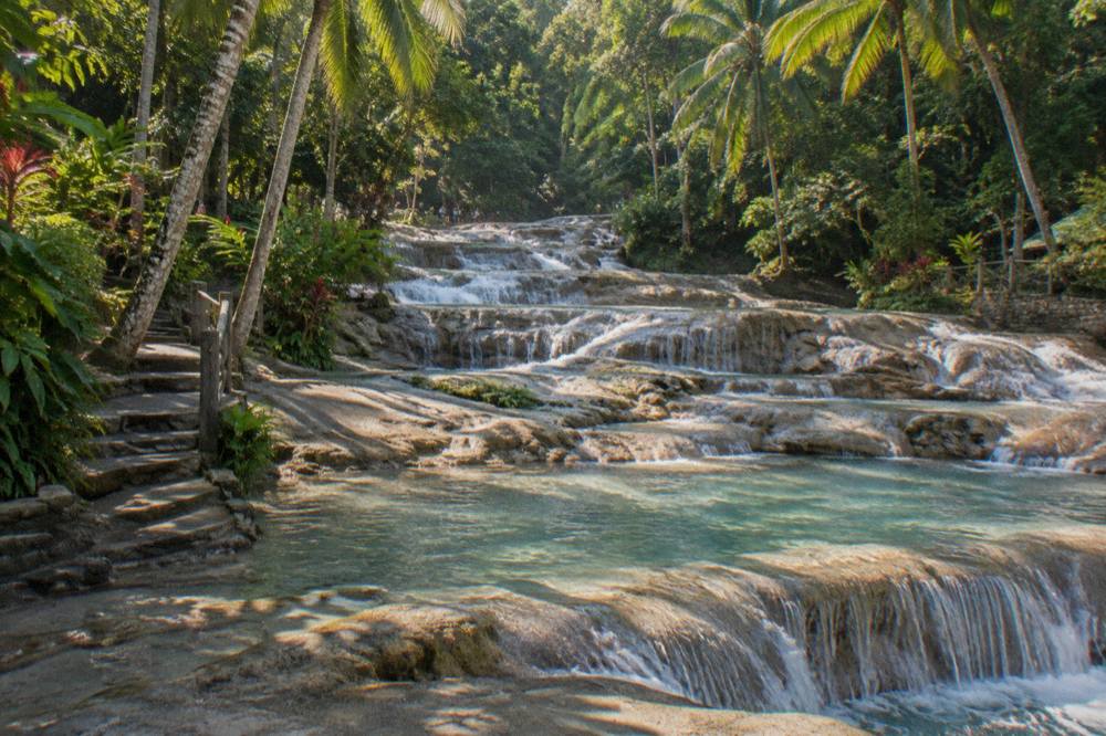 Morning light on a stepped waterfall with clear pools between rock terraces