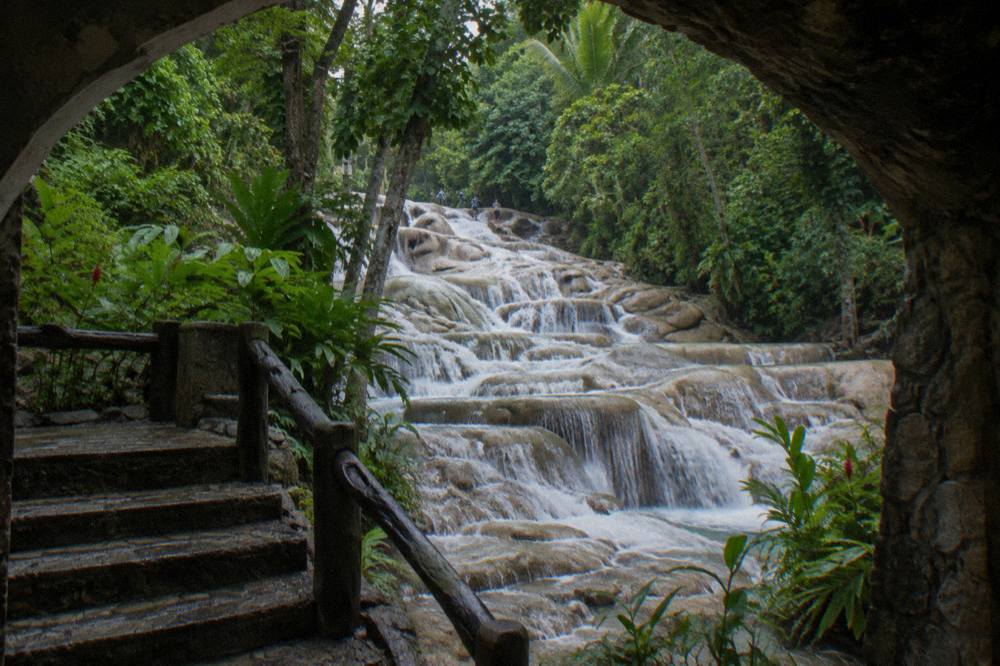 Cascading water spilling over stepped limestone terraces surrounded by green forest