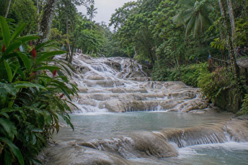 Swimmer resting in a terraced rock pool midway up a waterfall