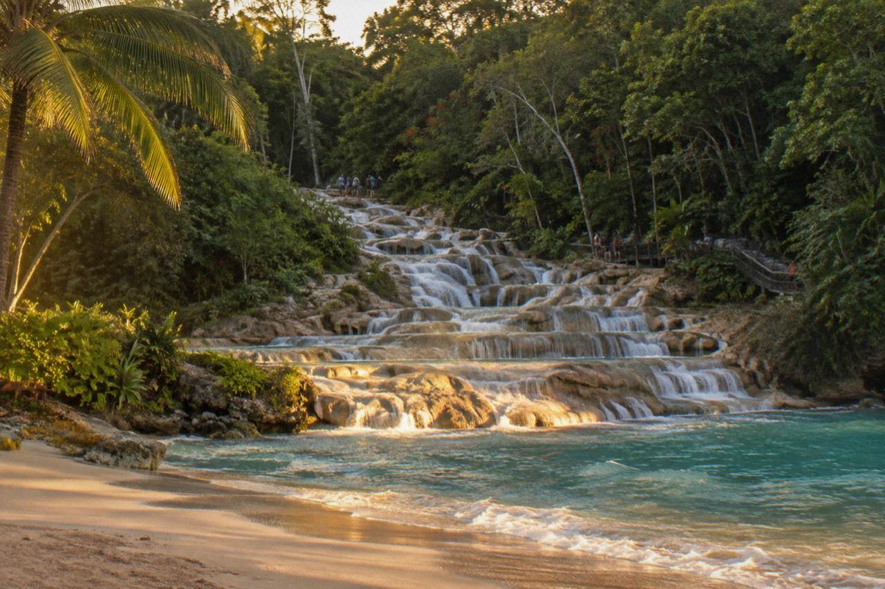 Terraced waterfall cascading over pale rock steps toward a sandy beach and the sea