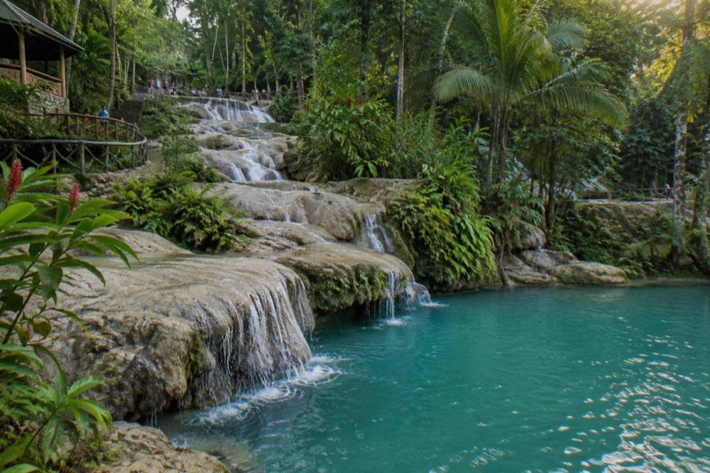 Turquoise waterfall pool surrounded by limestone rocks and tropical foliage