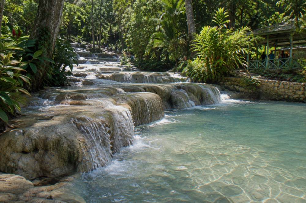 Water spilling over stepped limestone terraces into a clear pool