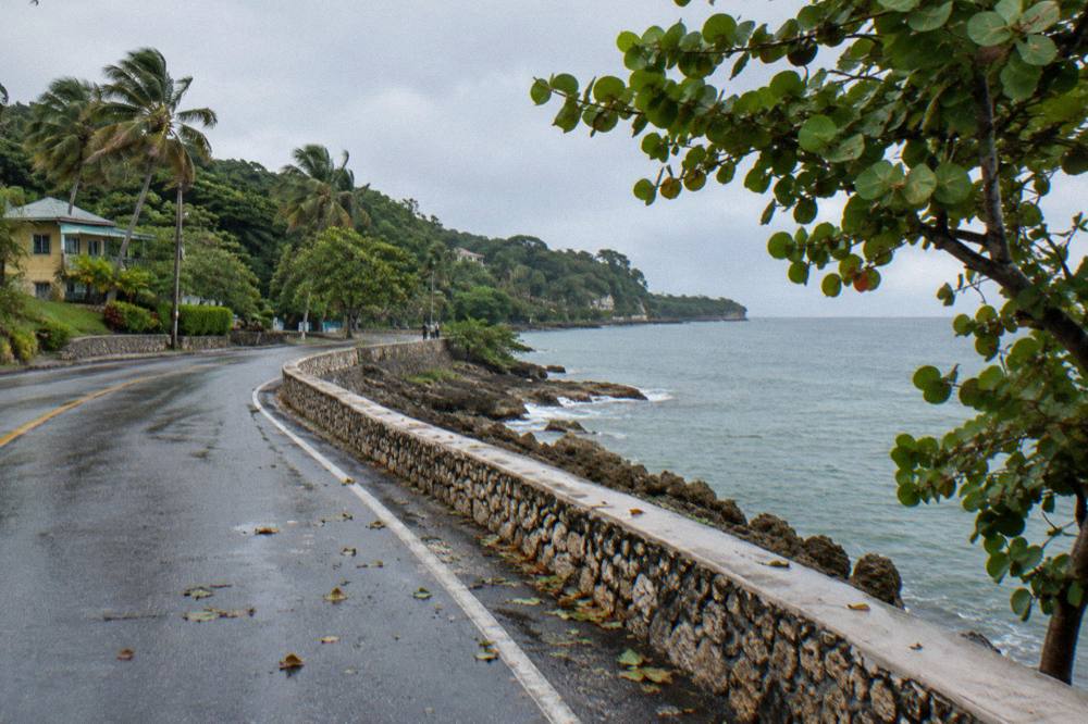 Coastal highway curving along the shoreline with calm Caribbean water on one side