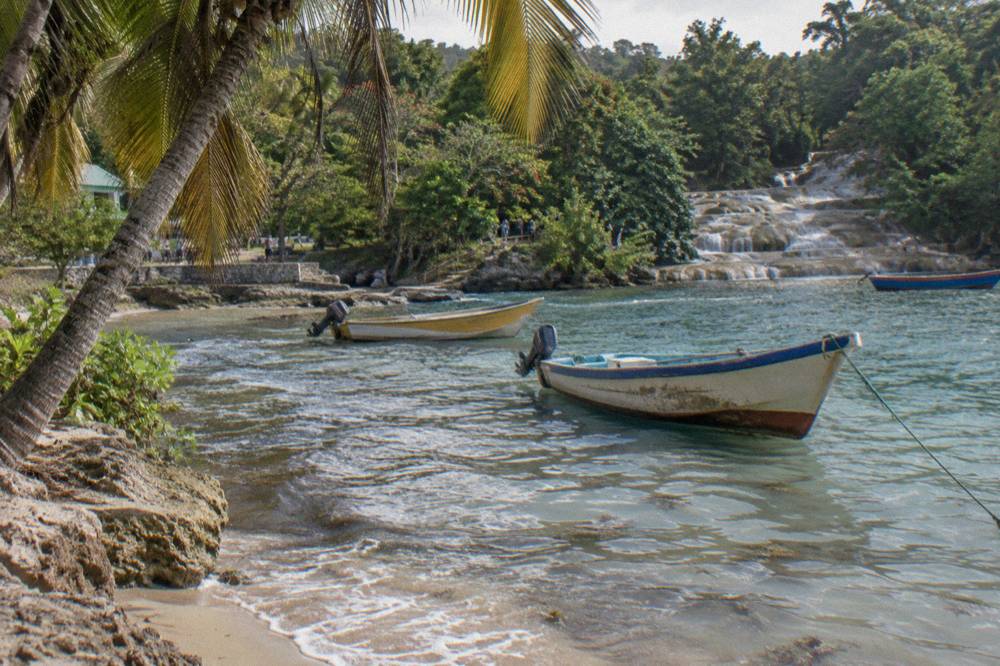 Golden light on a cove with fishing boats anchored on glassy turquoise water, palms and a coiled line on a bow