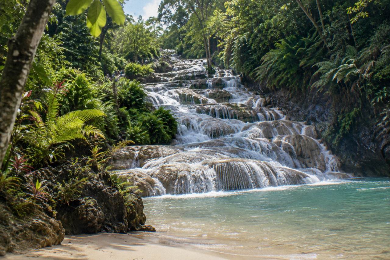 Terraced waterfall cascading through a green tropical gorge toward the sea