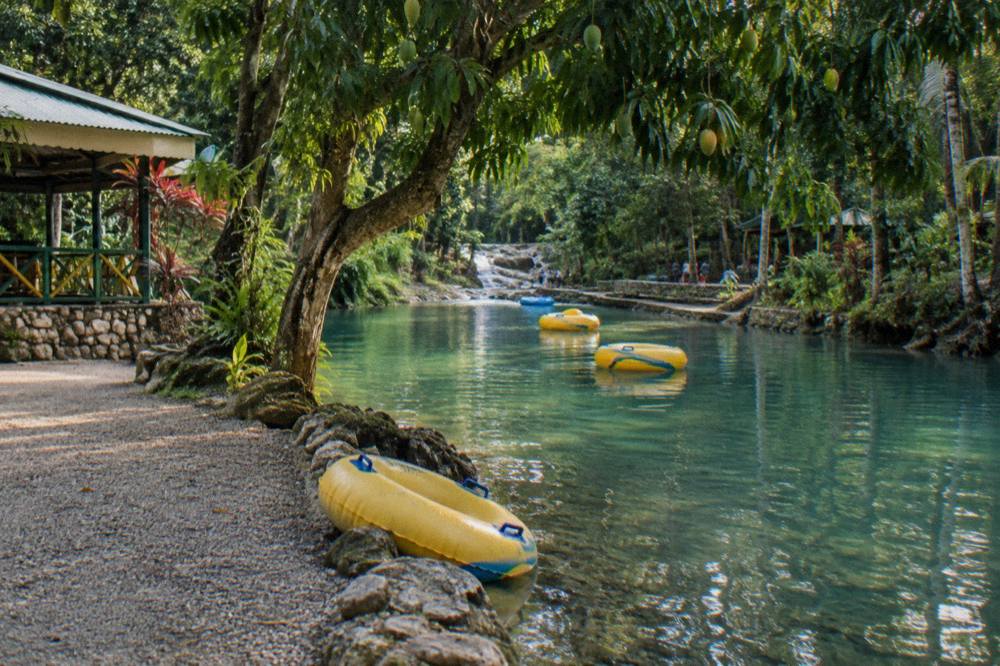 Inflatable tubes floating down a calm jungle river between overhanging trees