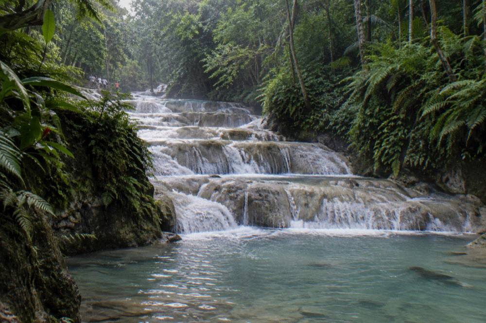 A terraced waterfall cascading over pale rock steps into a natural pool
