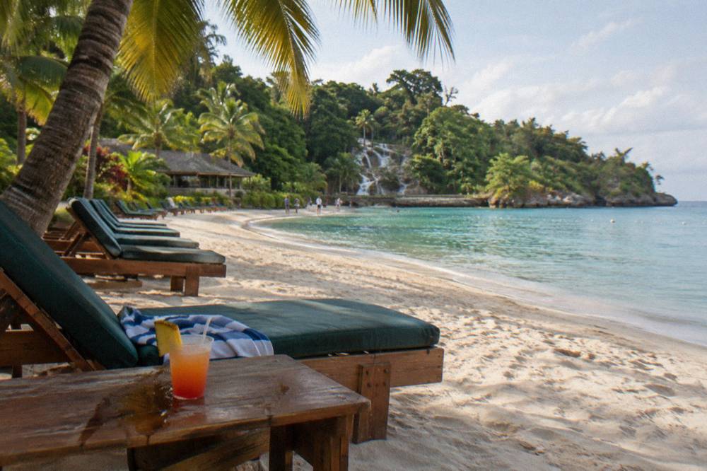 Palm-lined Caribbean beach with loungers and calm turquoise water along the Jamaican coast