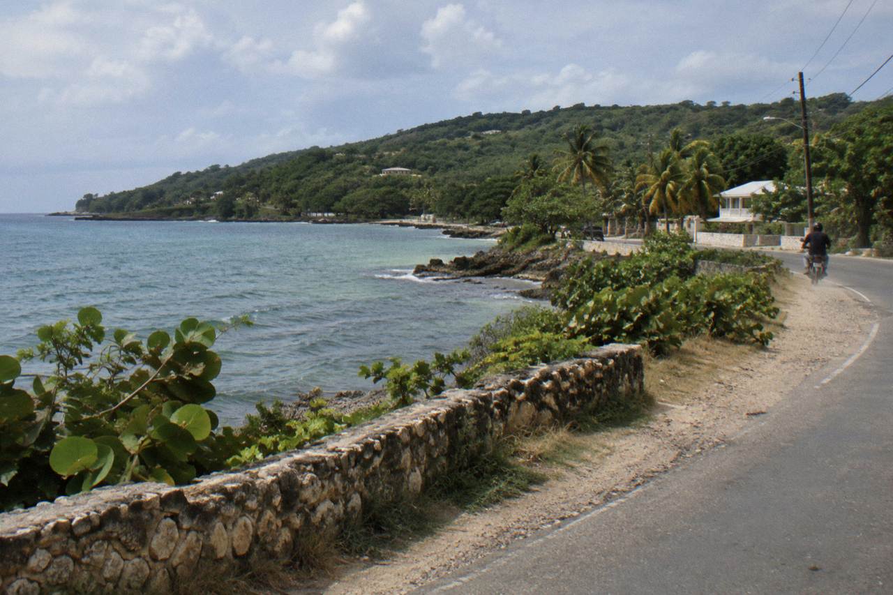 Coastal highway winding along the Jamaican north shore with turquoise water and green hills