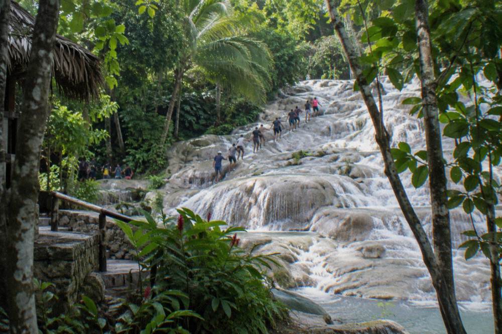 Crowded terraced waterfall with climbers forming a chain in the water