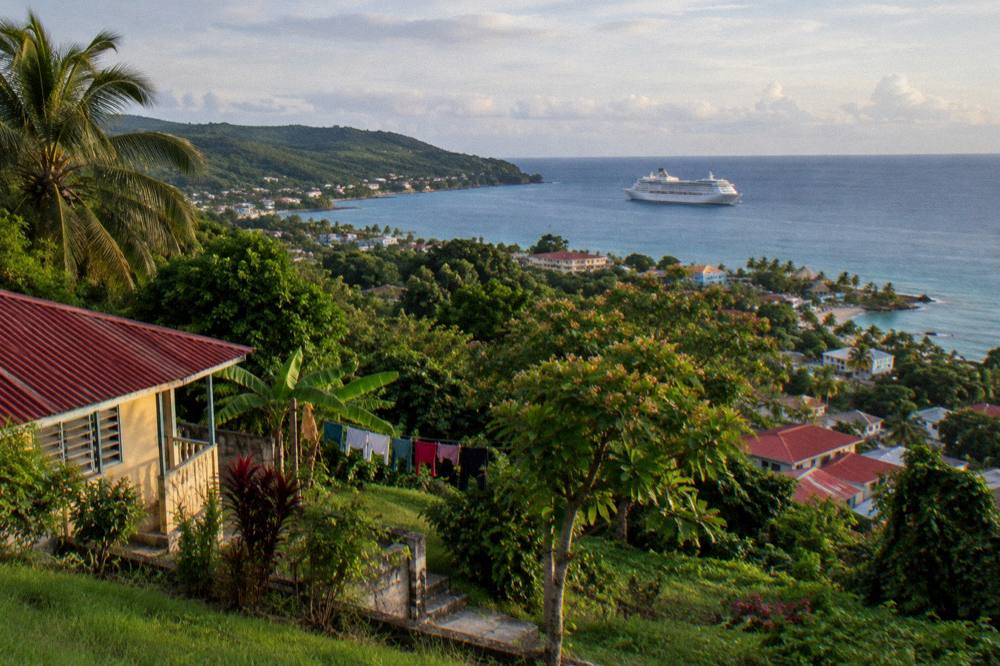 Cruise ship at anchor seen from a green hillside above a Caribbean bay
