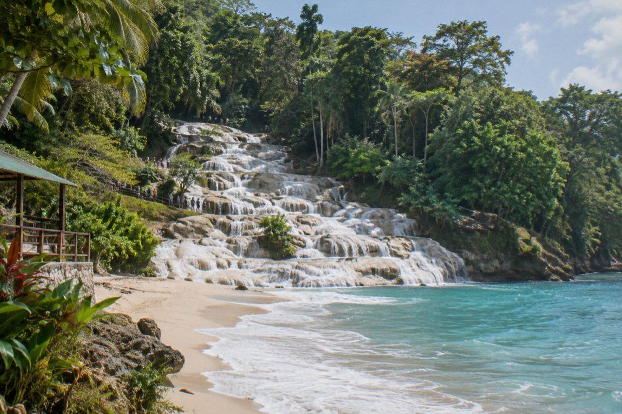 Terraced limestone waterfall cascading in steps toward a sandy beach and the Caribbean Sea