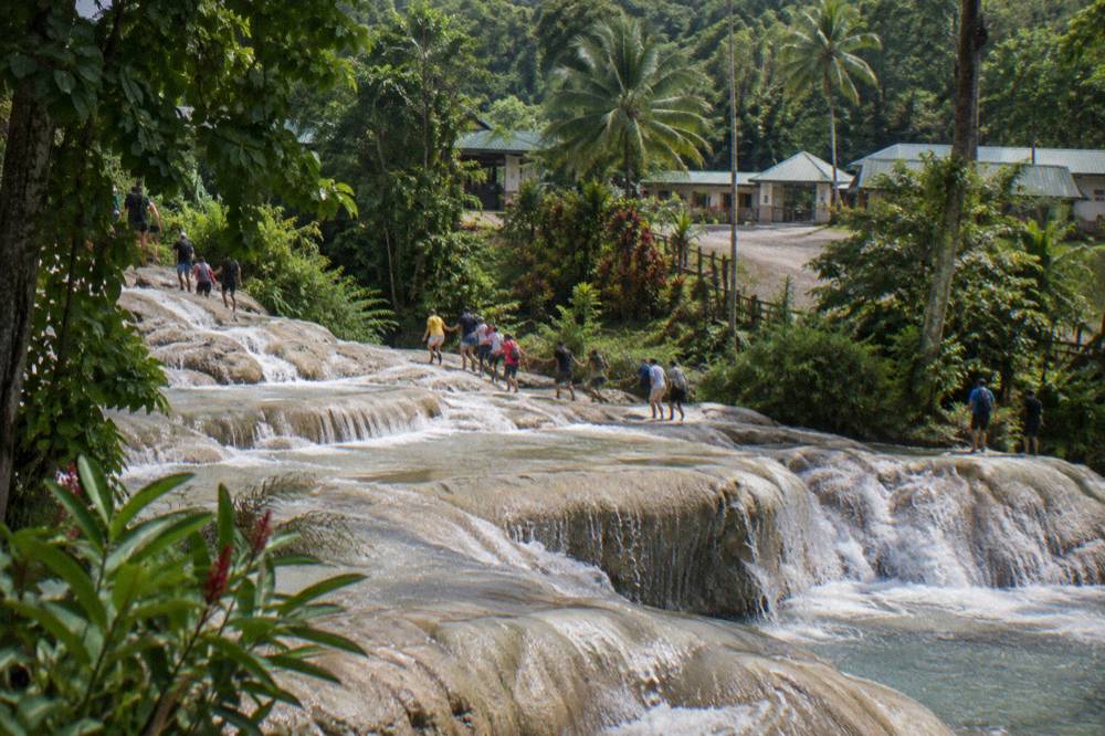 Crowded terraced steps of the waterfall with visitors climbing in a guided chain