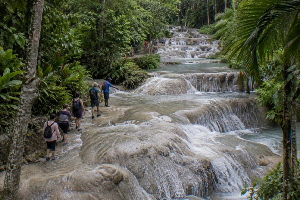Visitors forming a chain on the wet stone terraces partway up the waterfall