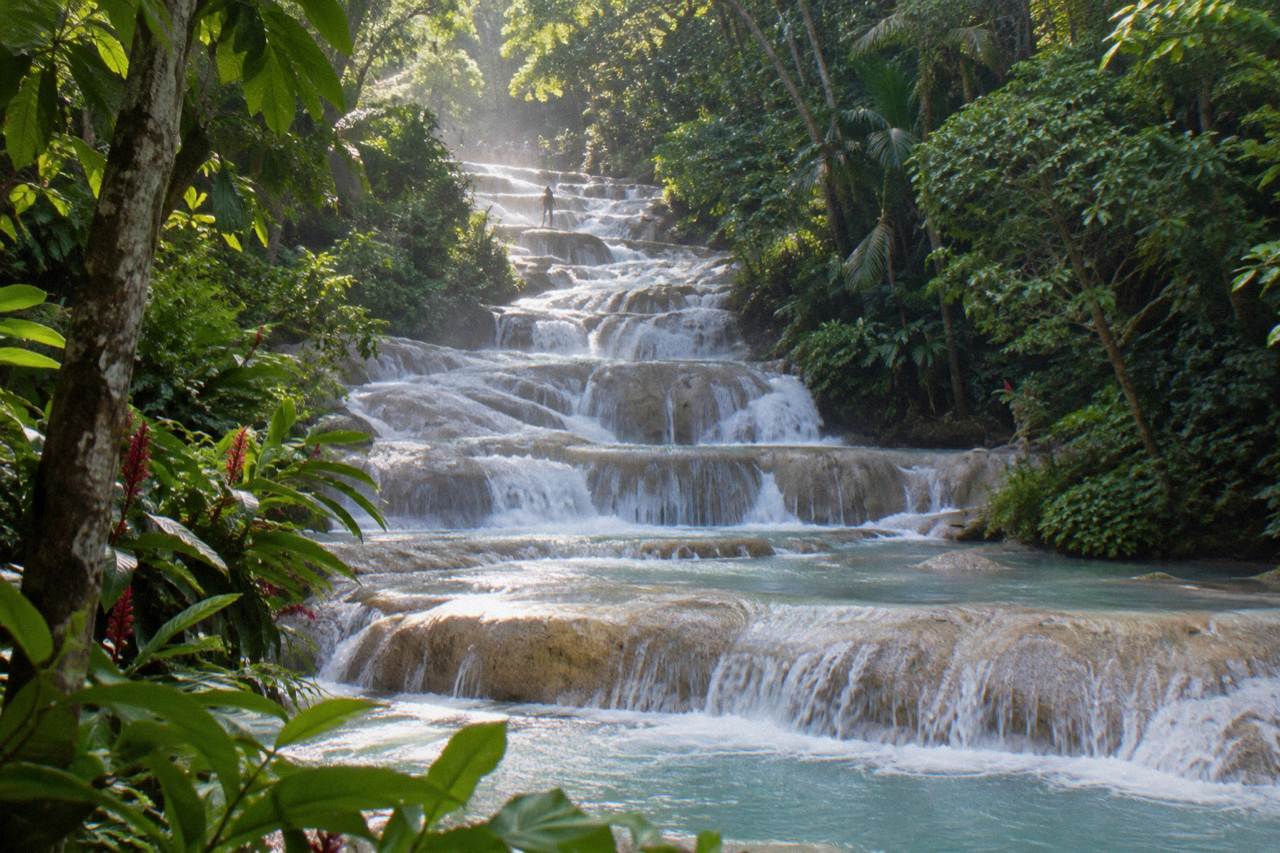 Terraced waterfall cascading through a green tropical gorge toward the Caribbean sea