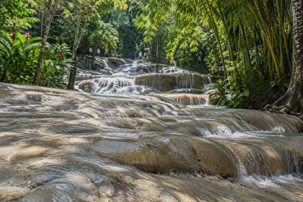 Water flowing over smooth terraced rock steps at a tropical waterfall
