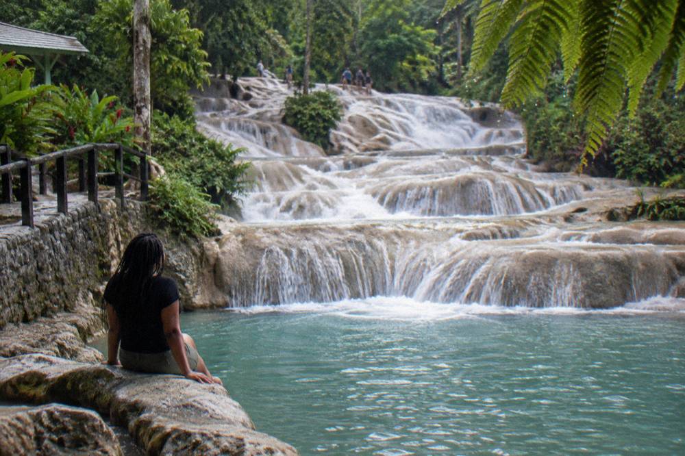 Visitors' water shoes and towels on rocks beside a cascading tropical waterfall