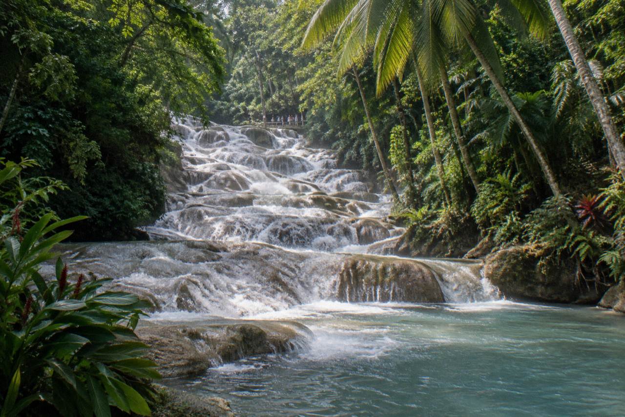 Terraced waterfall cascading through a green tropical gorge toward the sea
