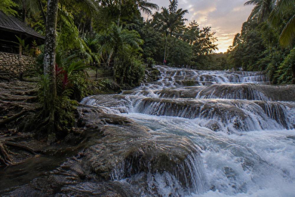 Close view of water rushing over layered limestone rock steps at a tropical waterfall