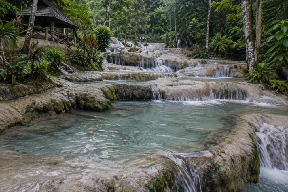 Shallow terraced limestone steps of a waterfall with water pooling in small basins