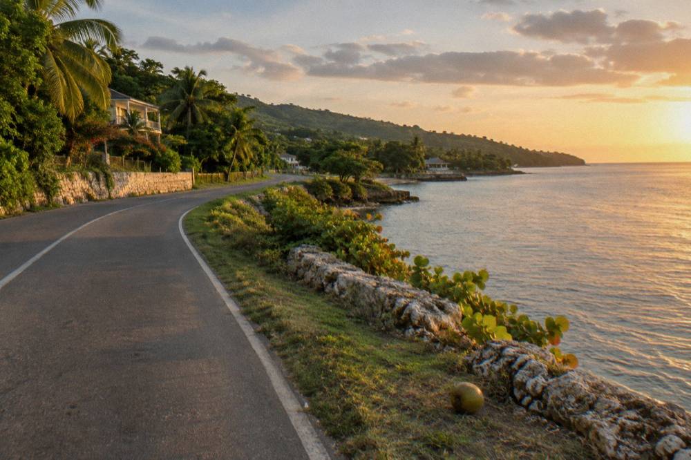 Coastal highway curving along green Jamaican shoreline with calm sea on one side