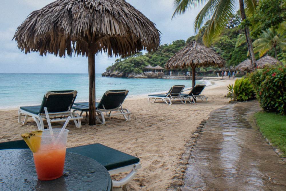 Beach chairs and thatched umbrellas on a sandy Caribbean beach club with calm turquoise water