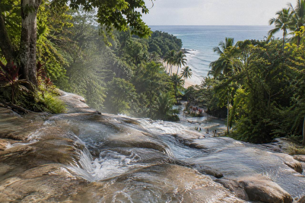 Terraced waterfall cascading through a green tropical gorge toward the Caribbean sea