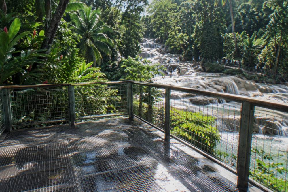 Crowded staircase and railing at a waterfall viewing deck with visitors in swimwear