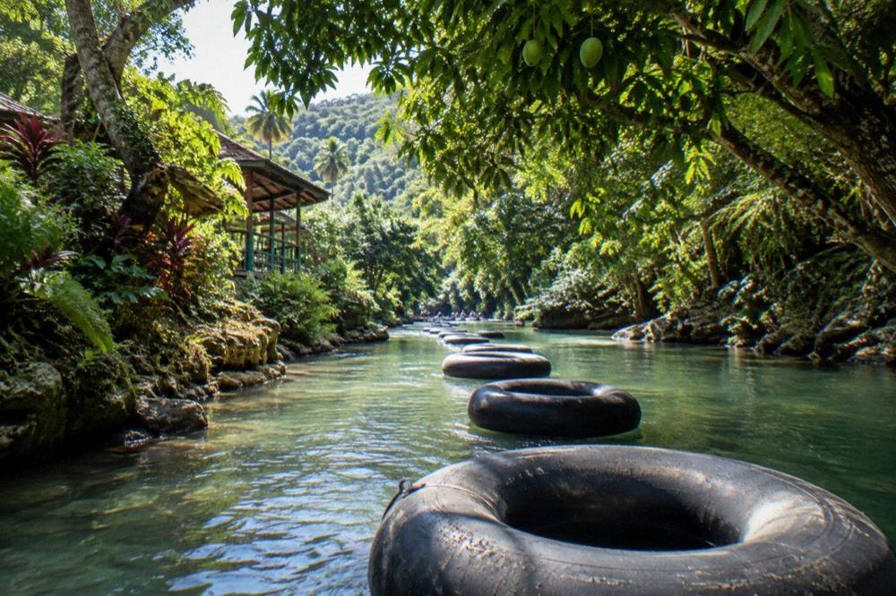 River rafts and tubes floating through a green tropical river corridor