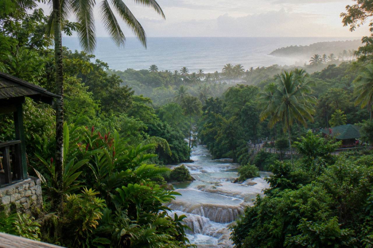 Terraced waterfall cascading through a green tropical gorge toward the Caribbean sea