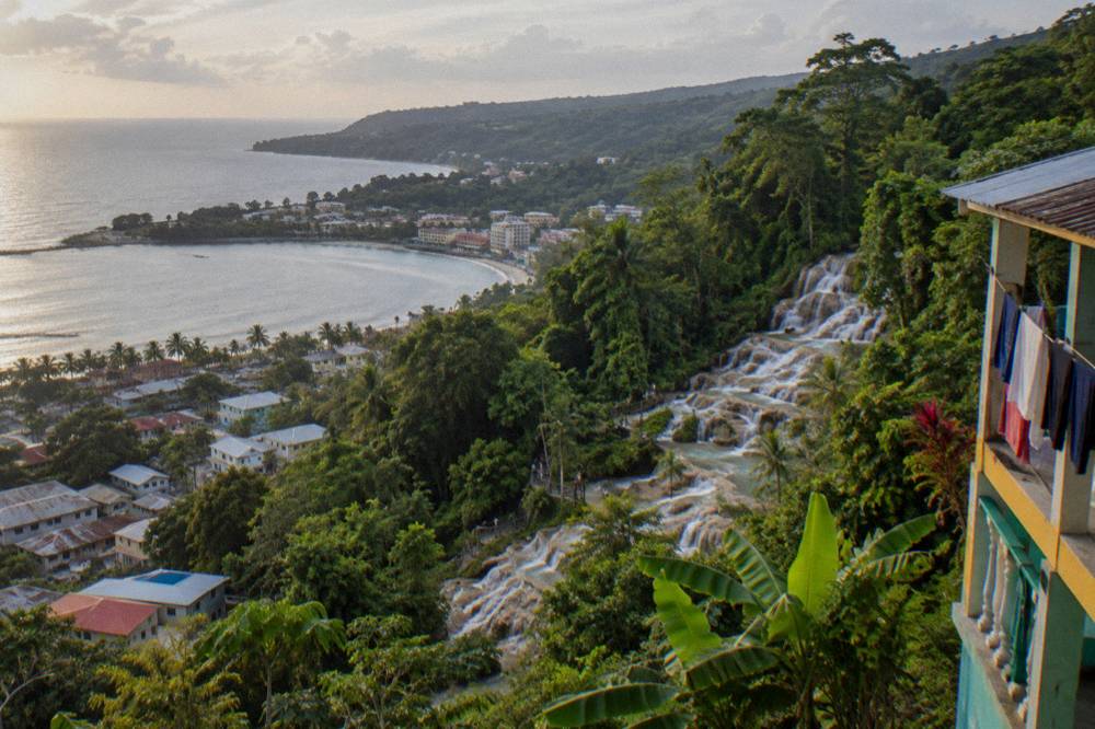 Aerial view of a small coastal town wrapped around a bay with green hills behind it